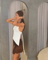 Minifalda marrón de cuero gamuzado con diseño cruzado y detalle de tachas metálicas.