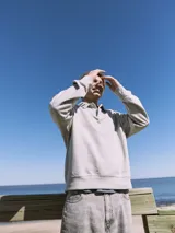 Polo de manga larga gris claro con cuello tipo camisa y cierre parcial con botones. Corte holgado y puños de canalé.