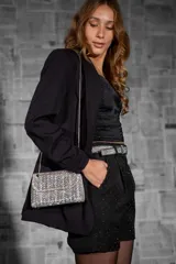 Cartera rígida dorada con acabado en strass y diseño geométrico. Tiene cadena metálica dorada para llevar al hombro o cruzada.