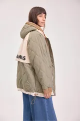 Campera acolchada reversible color verde militar, con capucha y cierre frontal con botones a presión.