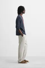 Pantalón color arena de corte recto, confeccionado en tejido de algodón y lino. Cuenta con cintura elástica ajustable con cordón, bolsillos delanteros y traseros de parche.