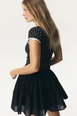 Top corto de manga corta, ajustado al cuerpo, con estampado floral pequeño en blanco sobre fondo negro. Presenta ribete de encaje blanco en el escote redondo y en los bordes de las mangas. El cuerpo principal parece ser de tejido acanalado.