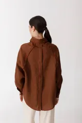 Camisa blanca de lino con botones de madera, corte recto y mangas largas.
