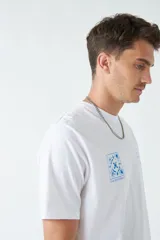 Remera marrón de algodón con cuello redondo, corte regular y estampado en el pecho. El modelo usa talle M.