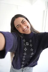 Sweater de punto azul marino con cuello redondo y mangas largas. Presenta textura trenzada en los laterales y detalle de estrellas bordadas en blanco en el centro, con la inscripción "Del Sur" en la parte superior.