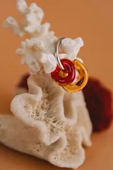 Aros colgantes hechos a mano con aro de acero quirúrgico y dijes circulares de cristal de Murano en color rojo y ámbar.