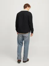 Sobrecamisa negra de manga larga con cuello clásico y fit relajado. Tiene cierre de botones, un bolsillo en el pecho y forro interno de borreguito color crema.