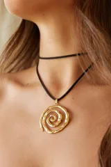 Collar con doble tira de gamuza negra y dije plateado en forma de espiral.