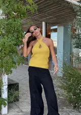 Top tejido color beige con lurex, de breteles finos y escote halter cruzado con abertura central.