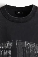 Musculosa negra con cuello redondo y sisas amplias. Estampado frontal con texto en color gris. Corte oversized.