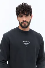 Buzo de algodón color negro lavado, con cuello redondo y estampado frontal en blanco con texto que incluye "BROOKSFIELD COVENT GARDEN LON UK". Presenta un pequeño parche negro en la manga izquierda.
