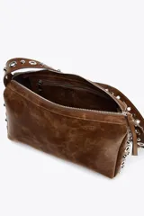 Bolso de hombro marrón con apliques metálicos plateados en los laterales y en la correa. Cierre con cremallera.