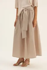 Falda larga color beige, de tafeta con moño en la cintura.