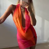 Vestido corto ajustado de microtul con estampado degradado en tonos vibrantes de naranja, fucsia y rosado. Diseño con cuello halter y escote pronunciado en cascada.