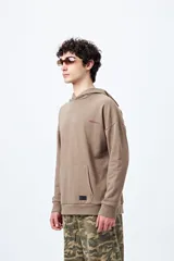 Canguro marrón con capucha, bolsillo frontal y puños ajustados. Estampa frontal con la palabra 'Dramatic' y gráfico en la espalda con tipografía bold y serpiente ilustrada.