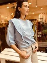 Camisa celeste a rayas verticales blancas, con cuello en V y mangas 3/4 abullonadas.