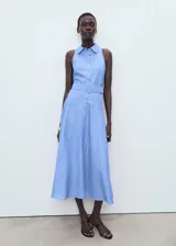 Vestido midi de algodón y lino, color celeste con rayas verticales blancas. Presenta cuello camisero, diseño sin mangas con tirantes anchos, cierre de botones frontales, cinturón con hebilla y falda evasé.