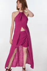 Conjunto de top halter con abertura en el abdomen y falda cruzada con ruedo desflecado, color fucsia.