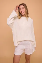 Buzo color crema tejido en algodón, de silueta holgada, mangas anchas y cuello bote.