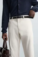 Pantalón chino de vestir negro, corte slim fit, con bolsillos laterales y traseros. Cierre frontal con cremallera y botón.