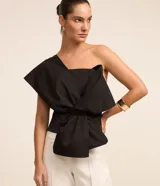 Blusa negra de tricolina con un hombro descubierto y un lazo grande en la parte delantera.