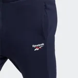 Pantalón de jogging azul marino de corte ajustado, con cintura elástica ajustable con cordón y bolsillos laterales. Logo de Reebok bordado en blanco en la pierna izquierda.