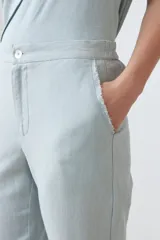 Pantalón celeste de lino, corte recto, con efecto desflecado en el ruedo.