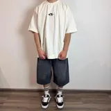 Remera color crudo de corte oversize y mangas cortas, con estampa en la espalda de una mano alcanzando un círculo.