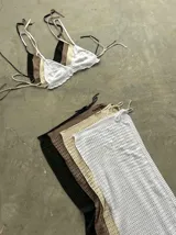 Conjunto de top halter a rayas horizontales marrones y blancas, y pollera larga blanca de hilo calado con tajo lateral.