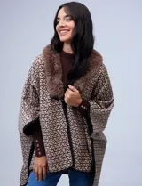 Ruana de tejido suave, color beige y marrón con estampado geométrico repetitivo. Posee cuello con aplique de piel sintética marrón y ribetes negros. Se combina con un suéter marrón de manga larga con botones en el puño.
