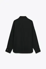 Camisa blanca de satén con cuello solapa y manga larga. Cierre frontal con botones dorados.
