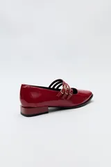 Zapato tipo Mary Jane color negro con textura de reptil, de charol sintético con punta cuadrada y triple tira con hebillas.