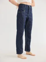 Pantalón de jean azul oscuro, de corte recto, con pespuntes en color amarillo claro y detalles de atraques.
