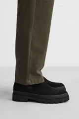 Bota Chelsea negra de cuero con acabado serraje, caña baja, puntera redondeada, tirador trasero y suela track con volumen.