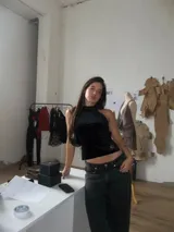 Top halter negro de terciopelo con silueta ajustada y caída recta. Presenta un diseño abierto en la espalda con finas tiras ajustables que se anudan al cuello y a la cintura.