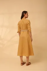 Vestido midi color mostaza, estilo camisero, con cuello mao, mangas 3/4 y cinturón trenzado.