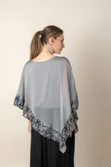 Blusa tipo poncho color gris con zócalo de tul bordado con motivos florales negros. Incluye una camiseta interior de spandex.