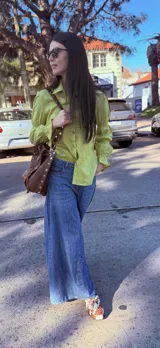 Camisa color verde lima confeccionada en lino, de corte holgado, con cuello camisero, mangas largas abullonadas con puños elásticos y cierre frontal con botones.