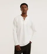 Remera blanca de manga larga con cuello redondo y cordones ajustables en el escote.