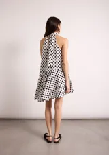 Vestido corto negro con cuello halter y falda con vuelo asimétrico.