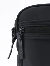 Morral bandolera negro con cierre superior y bolsillo frontal con cierre.