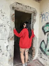 Buzo de tejido de punto color rojo, con cuello redondo y ribete celeste. Presenta costuras blancas visibles en hombros y mangas.