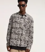 Camisa masculina de franela con estampa de cuadros en tonos grises y blancos, cuello inglés, abotonada, manga larga, modelo comfort con bolsillo en el pecho.