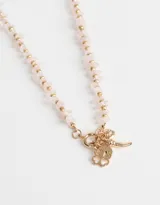 Collar corto dorado con cadena de eslabones, piedras naturales rosas y dijes colgantes dorados.
