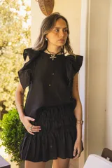 Blusa negra de lino con volados en los hombros y pespuntes en color beige.