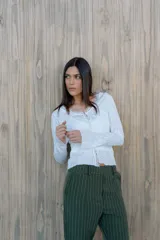 Remera de encaje blanca con mangas largas y broche metálico en el centro. Incluye musculosa de lycra blanca como forro.