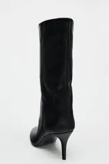 Bota de cuero sintético color negro, con caña media de efecto arrugado, punta fina y tacón fino.