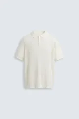 Polo blanco de punto tejido con estructura calada, corte regular fit, cuello solapa con abertura frontal y manga corta.