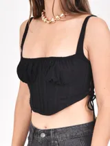 Top negro con corte irregular, breteles anchos y lazos laterales.