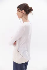 Remera color blanco con detalles en gris, de manga larga y corte suelto.